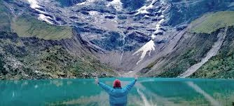 Caminhantes em uma trilha de montanha com paisagens majestosas e um pico nevado ao fundo, ilustrando a beleza desafiadora da Trilha Salkantay, ideal para a Machu Picchu melhor época.
