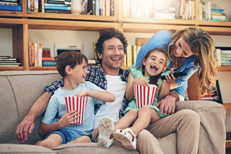Família reunida no sofá se preparando para assistir a um filme infantil educativo
